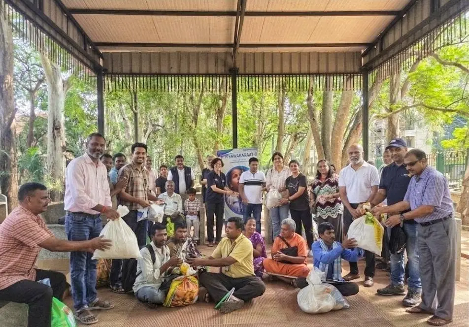 Rotary club members and community volunteers distributing supplies at a park pavilion during a Vishwabarathu service project